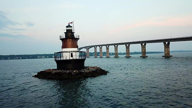 Flying past an ocean lighthouse with bridge